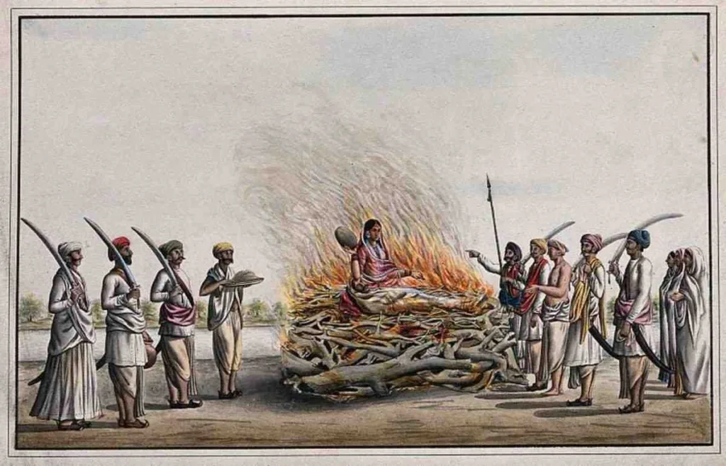A historical illustration showing a widow standing by her husband’s funeral pyre (Sati).